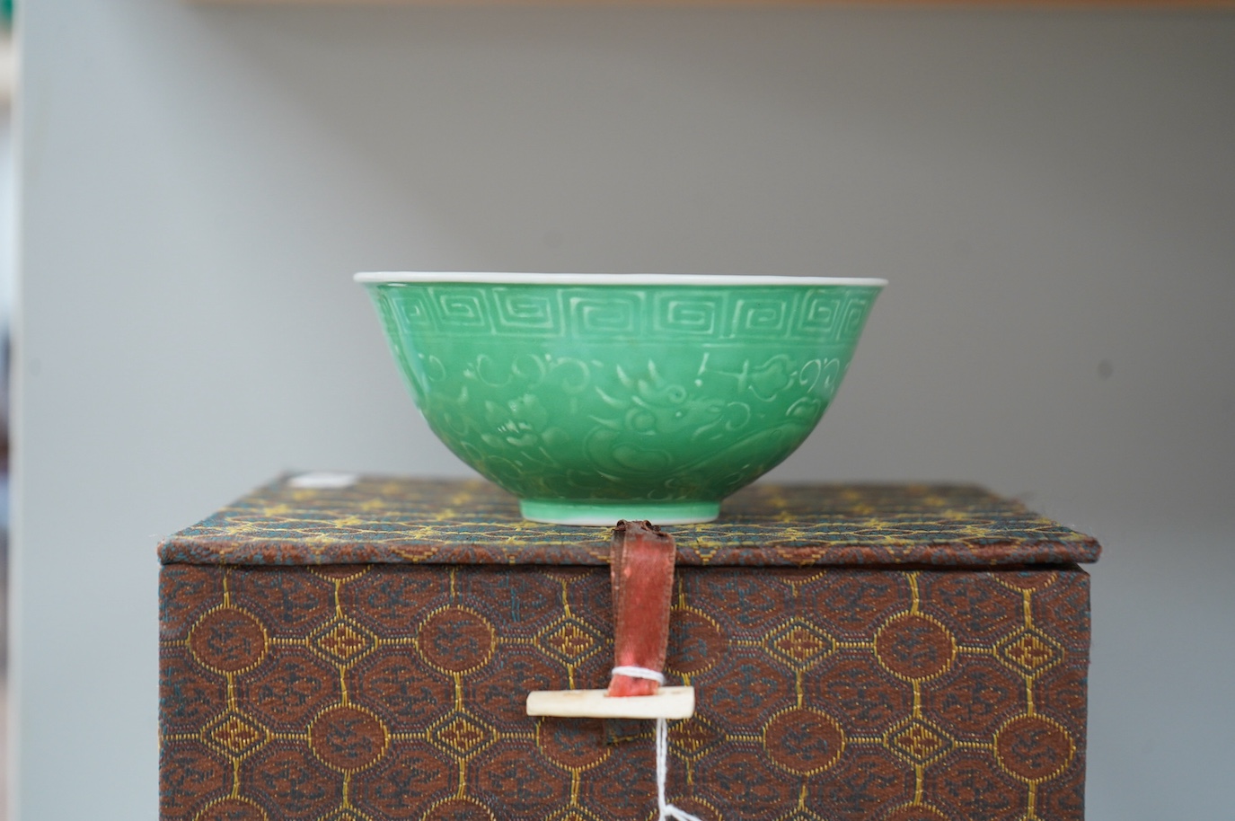 A set of four Chinese green glazed and moulded bowls and a famille rose dish, 19th and 20th century, boxed, largest 17cm. Condition - one bowl cracked